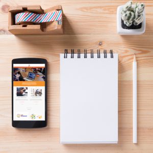 Topview of office stuff on wooden working table. Mock up. Sticky tape, note paper , white blank notebook, post-it note, pencil and blank white screen smartphone.