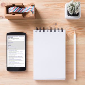 Topview of office stuff on wooden working table. Mock up. Sticky tape, note paper , white blank notebook, post-it note, pencil and blank white screen smartphone.
