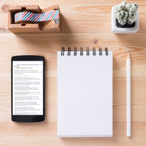 Topview of office stuff on wooden working table. Mock up. Sticky tape, note paper , white blank notebook, post-it note, pencil and blank white screen smartphone.