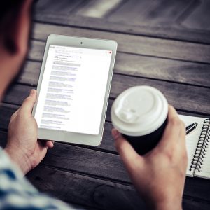 Young man using digital tablet while drinking Coffee sitting at home garden, Relaxing in the morning.